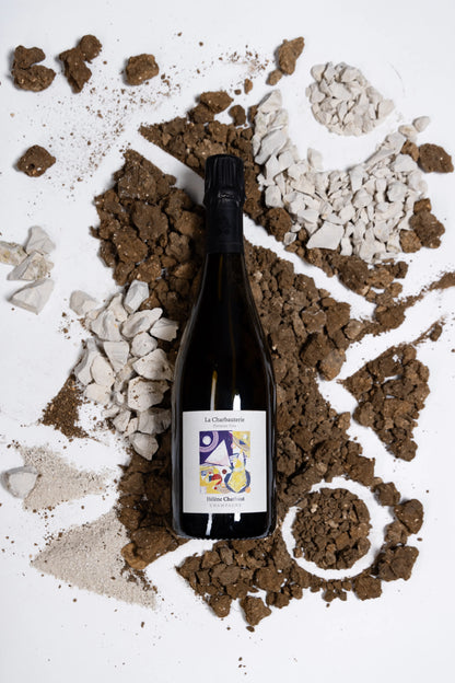 Eine Flasche des Winzerchampagners La Charbauterie von Hélène Charbaut wird umrahmt von Kalk- und Kreidesteinen die den Boden repräsentieren sollen auf dem die Trauben wachsen.